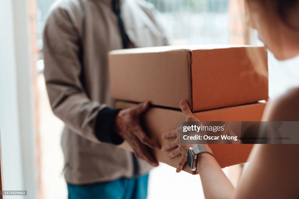 Closeup of delivery person handing in a package to customer