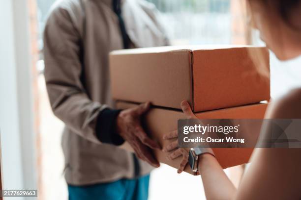 closeup of delivery person handing in a package to customer - delivering stock pictures, royalty-free photos & images