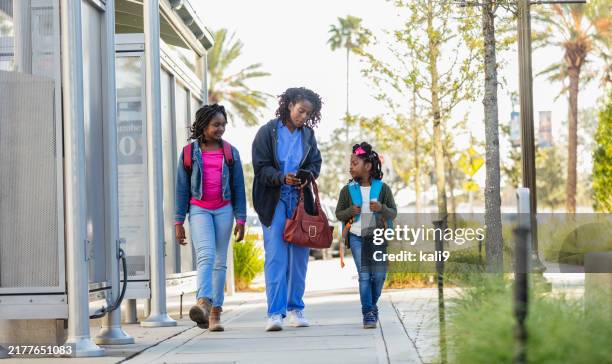 una madre lavoratrice afroamericana porta le figlie a scuola - famiglia con due figli foto e immagini stock