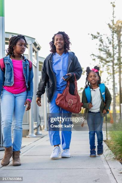 una madre lavoratrice afroamericana porta le figlie a scuola - famiglia con due figli foto e immagini stock