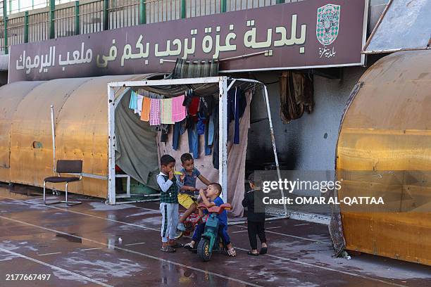 Children play near a goal post at a makeshift camp for Palestinians displaced from northern Gaza, at Gaza City's damaged Yarmouk stadium on October...