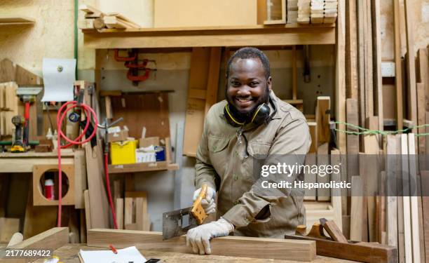 man working at a carpentry shop cutting wood using a manual saw - work gloves stock pictures, royalty-free photos & images