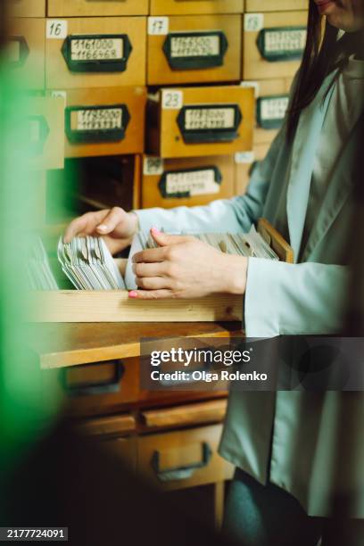 book lookup in card catalog: woman hands search for card in public library archive. - archives stock pictures, royalty-free photos & images
