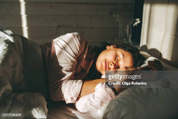 sleep deprivation: tired woman finally sleeps under bright morning sun in bedroom - schlafen stock-fotos und bilder