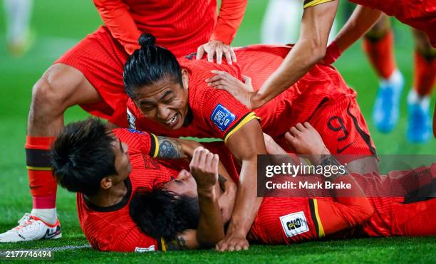 Wenneng Xie of China PR celebrates after scoring his teams first goal with Penhfei Xei and Yuning Zhang of China PR during the third round FIFA World...