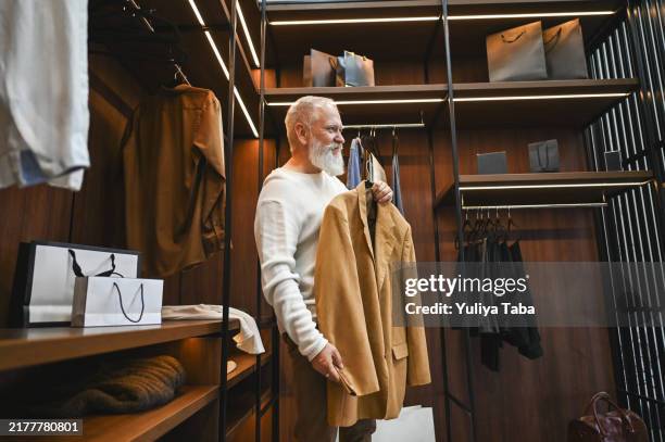hombre mayor comprando ropa en una tienda departamental. - gran almacén fotografías e imágenes de stock