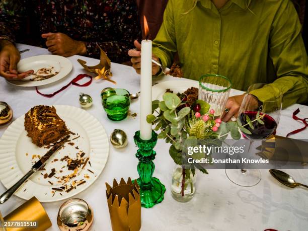 friends enjoying chocolate christmas yule log cake at table - kaarslicht stockfoto's en -beelden