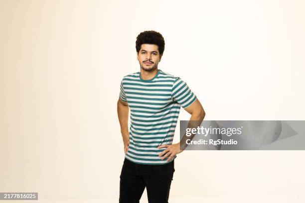 middle eastern man striking a relaxed pose in a studio setting - plain tshirt stock pictures, royalty-free photos & images