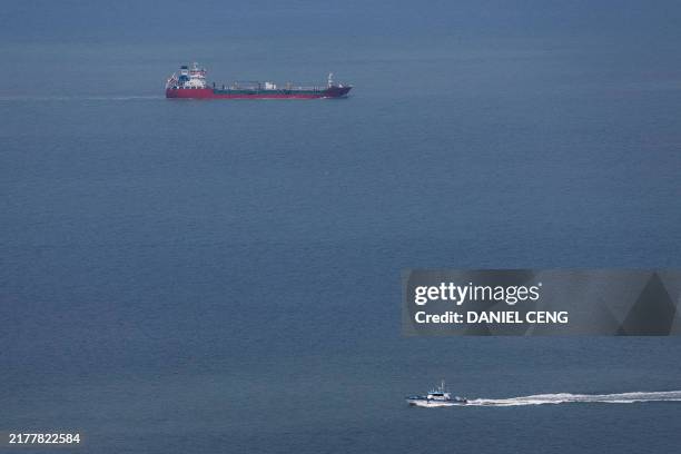 Taiwanese Coast Guard vessel patrols as a cargo vessel sails toward mainland China, off the coast of the Matsu Islands on October 15 a day after...