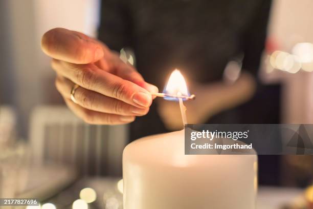 mère allumant une bougie pendant le souper de la veille de noël. - allumer photos et images de collection