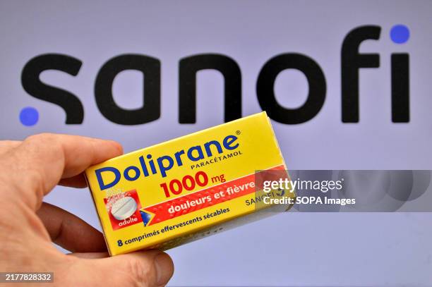 In this illustration photo, a hand holds a box of Doliprane tablets in front of the Sanofi company logo. The French pharmaceutical group Sanofi has...