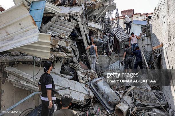 People gather outside a collapsed building as they attempt to extricate a man from underneath the rubble following Israeli bombardment in the Saftawi...