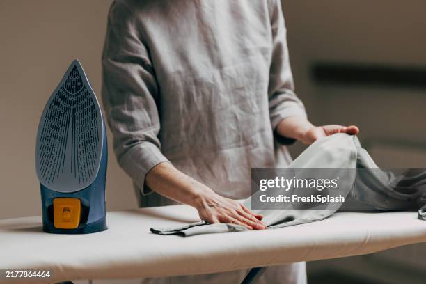 person ironing clothes with modern steam iron on board - polishing stock pictures, royalty-free photos & images