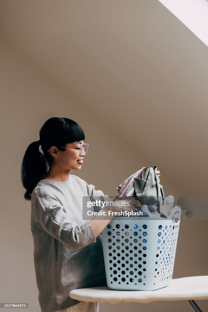 Woman Sorting Laundry in a Bright Attic Room Setting