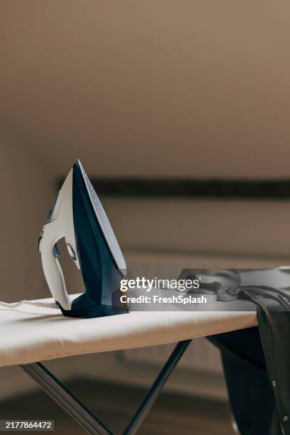 electric iron on ironing board with a shirt in modern home - tábua-de-passar-roupa imagens e fotografias de stock