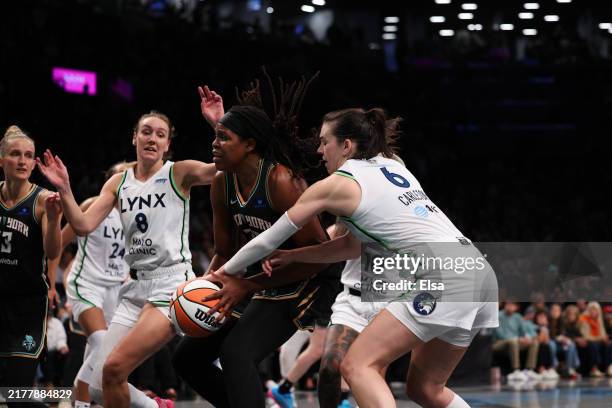 Jonquel Jones of the New York Liberty drives to the basket against Bridget Carleton and Alanna Smith of the Minnesota Lynx in over time during Game...