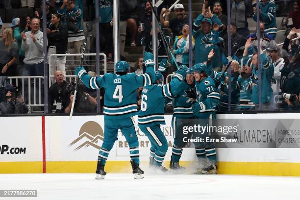Macklin Celebrini of the San Jose Sharks is congratulated by teammates after he scored his first career NHL goal against the St. Louis Blues in the...