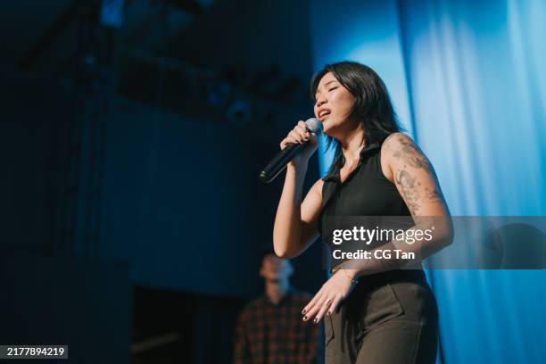 cantante pop femminile cinese che canta insieme alla performance dal vivo del gruppo multirazziale sul palco - musicista di musica pop foto e immagini stock