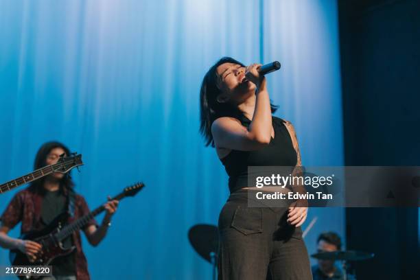 chinese female pop lead singer singing together with multiracial group live band performance on stage - musician stock pictures, royalty-free photos & images