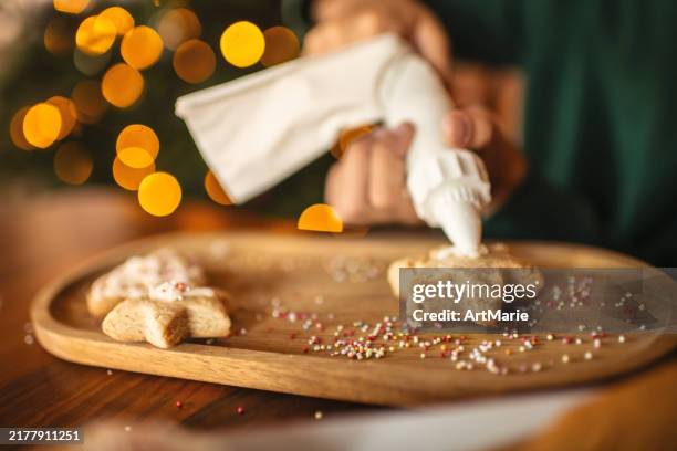 boy icing christmas cookies - nagerecht-garnering stockfoto's en -beelden