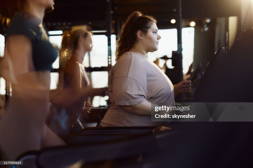 Young obese woman exercising on treadmill in a health club.