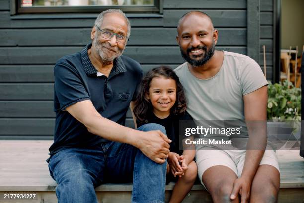 portrait of smiling boy sitting with father and grandfather on porch - generation gap stock pictures, royalty-free photos & images