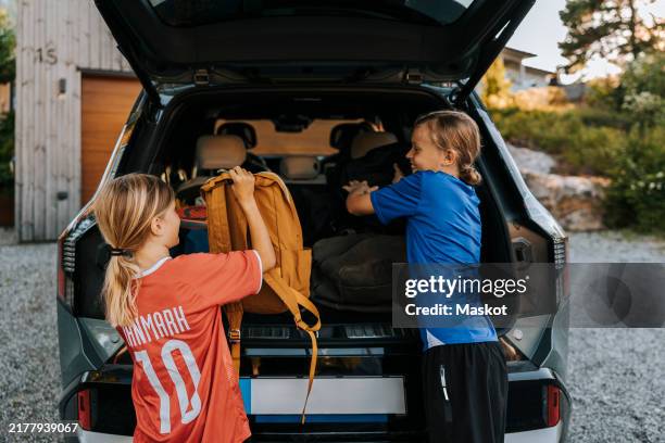 boys loading backpacks in car trunk while standing on driveway - converse boots stock pictures, royalty-free photos & images