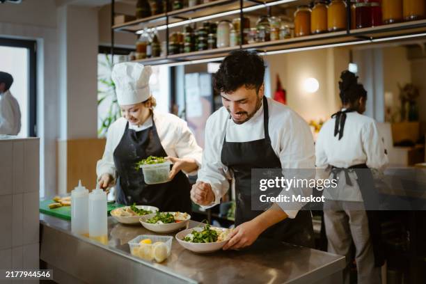 male and female chefs preparing food at commercial kitchen in restaurant - chef cuisinier photos et images de collection