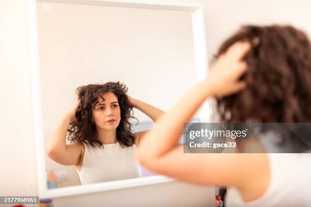 mujer examinando su cabello - mano en el cabello fotografías e imágenes de stock
