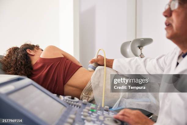 with concentration, the doctor reviews the ultrasound during the young patient's kidney examination. - nephrology stock pictures, royalty-free photos & images