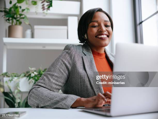 selbstbewusste professionelle frau, die am laptop im modernen büro arbeitet - super computer stock-fotos und bilder