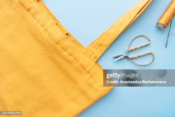 sewing yellow handbag with threads and scissors on blue background - green purse stock pictures, royalty-free photos & images