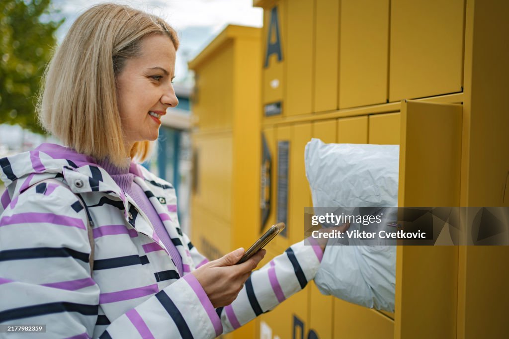 Junge erwachsene Frau, die ein Paket aus einem intelligenten elektronischen Schließfach abholt