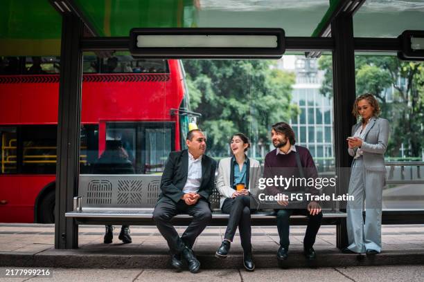 coworkers talking in a bus stop in the city - bus stop stock pictures, royalty-free photos & images