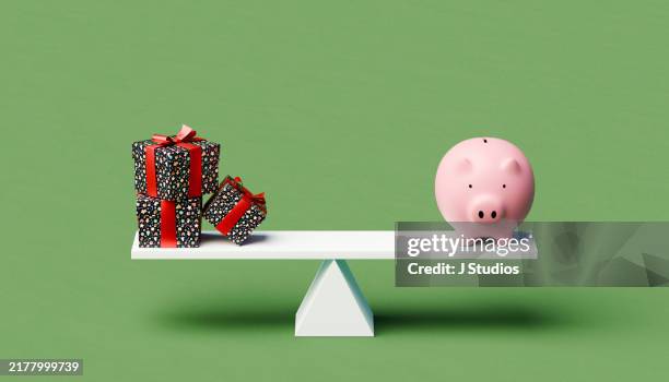seesaw with a piggybank and a tree christmas gifts - december stockfoto's en -beelden