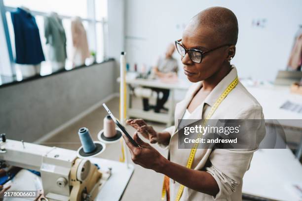 portrait d’une couturière à l’aide d’une tablette numérique - industrie de la mode photos et images de collection