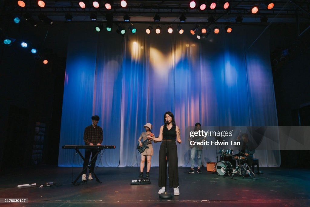 Young Asian chinese lead singer and live band Multiracial group performance on stage