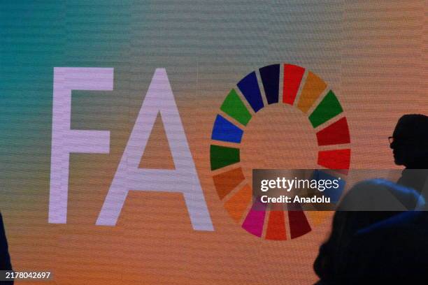 Participants stand in front of a screen displaying the FAO logo during a conference on global food security and sustainable development, with the UN...