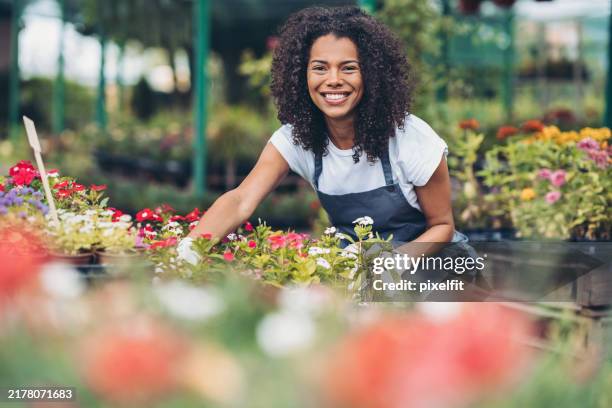 happy young woman working in a garden center - tuincentrum stockfoto's en -beelden