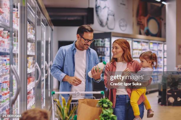 happy family shopping together in a supermarket dairy aisle - stormarknad bildbanksfoton och bilder