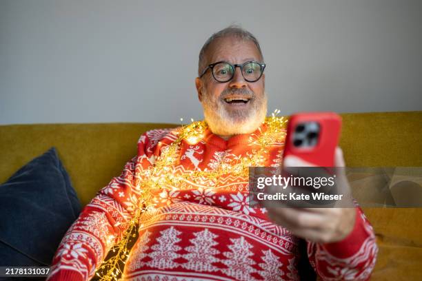 christmas sweater senior man taking selfie - christmas sweater stock pictures, royalty-free photos & images