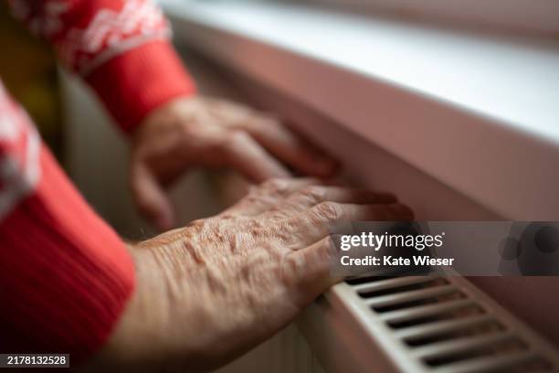 hands of senior man warming himself from the radiator - electric fire stock pictures, royalty-free photos & images
