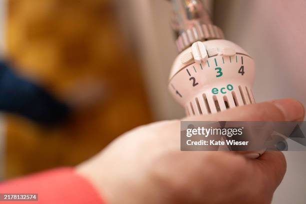 a man's hand turns the battery-powered radiator. - huisverwarming stockfoto's en -beelden