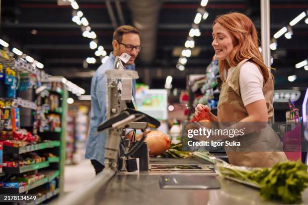 grocery store interaction between friendly cashier and customer - caixa registadora imagens e fotografias de stock