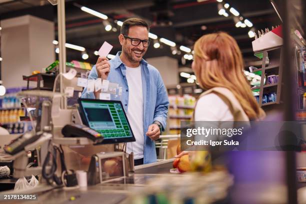 friendly customer and cashier interaction in a supermarket checkout - caixa registadora imagens e fotografias de stock