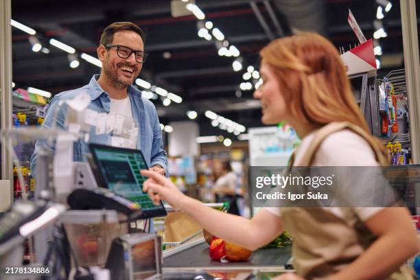 freundliche interaktion zwischen kunde und kassierer an der supermarktkasse - ladenkasse stock-fotos und bilder