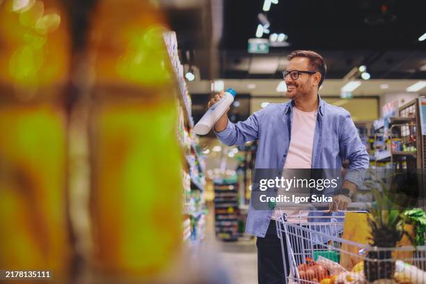 male customer choosing detergent from shelf - waschmittel stock-fotos und bilder