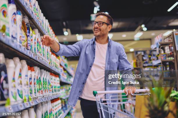 cliente masculino eligiendo detergente de estante - mercado espacio de comercio fotografías e imágenes de stock