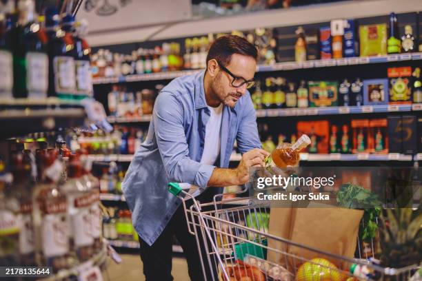 man at the supermarket looking for some alcohol - whiskey label stock pictures, royalty-free photos & images