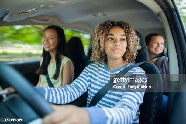 giovane ragazza adolescente multirazziale che guida l'auto mentre l'amico asiatico si siede in auto con il passeggero degli amici - trasporto collettivo foto e immagini stock